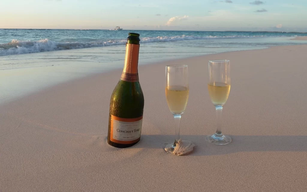 bottiglia di spumante con due bicchieri su spiaggia di aruba
